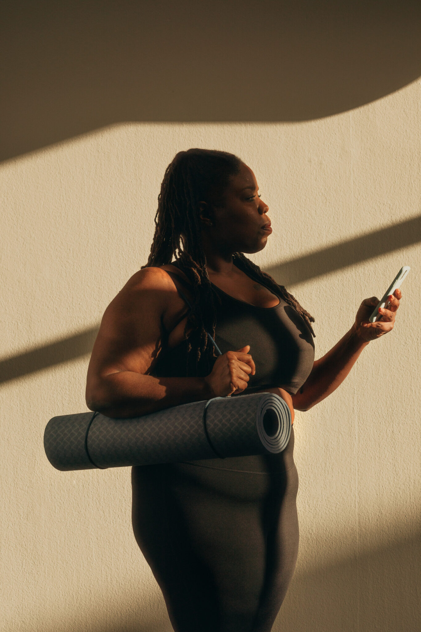 woman holding yoga mat on the phone